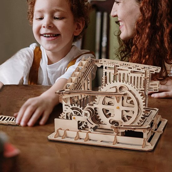 jeu de construction en bois mécanique​ sur la table avec fille